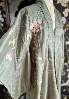 A rather beautiful, vintage Japanese kimono robe, dating to the late 1930s. Made of a soft, pale sage green silk with silk hand embroidery of leaves and roses. Also lined in silk and completely hand stitched. It has the odd issue. A mark to the right hand sleeve and right lapel as photographed. Also a nibble near to the hem area. These are not hugely apparent defects and as a whole this presents beautifully. Photographed on my UK size 8 mannequin. Nape to hem 55" Back of shoulders 25.5" Luxury Green Elegant Kimono, Traditional Luxury Green Kimono, Green Kimono Traditional, Green Yukata, Ceremonial Vintage Kimono, Vintage Kimono With Floral Embroidery, Green Kimono, Vintage Japanese Kimono, Japanese Silk