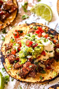 two tacos with meat, guacamole and sour cream on the side