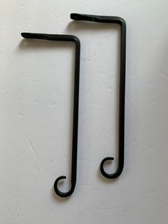 two black metal hooks on a white wall