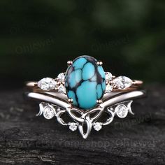 a turquoise ring with white diamonds on it sitting on top of a piece of wood