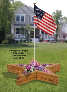 an american flag is placed in the center of a raised garden bed with flowers on it