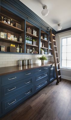 a kitchen with blue cabinets and wooden ladder in the center, next to a window