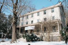 a large white house sitting next to trees covered in snow