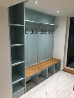 an empty room with two benches and several storage units on the wall, along with wooden flooring