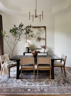 a dining room table with chairs and a rug on the floor in front of it