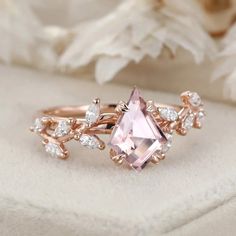 an engagement ring with a pink stone surrounded by white diamonds on top of a flower