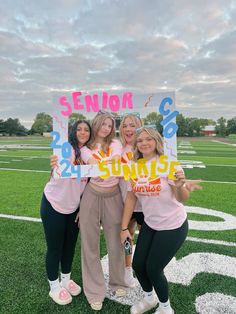 three girls holding up a sign that says senior and 21 sunrise on the sidelines