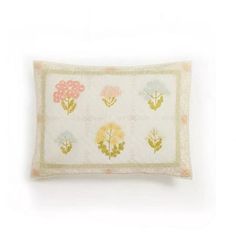 an embroidered pillow with flowers on it, sitting on a white wallpapered surface