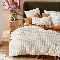 a bed with white and brown comforters in a bedroom next to a nightstand table