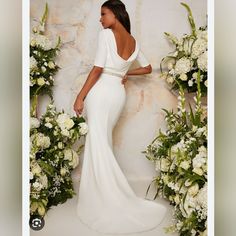 a woman in a white dress standing next to flowers