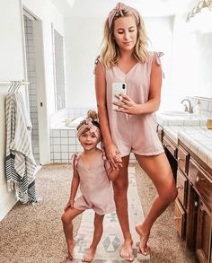 a mother and her daughter taking a selfie in the bathroom while they both wear matching outfits