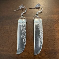 two pairs of silver earrings on a wooden table