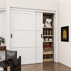 an open pantry door in the corner of a room next to a chair and table