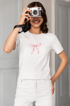 Add a touch of sweetness to your wardrobe with this adorable pink bow t-shirt! This women's t-shirt features a charming pink bow printed design that is both cute and stylish. Made from high-quality materials, this top is perfect for adding a pop of color to any outfit. Whether you're heading out for a casual day out or just want to add a fun element to your look, this sweet pink bow t-shirt is sure to become a favorite in your collection. Feminine Pink Crew Neck T-shirt, Casual Short Sleeve T-shirt With Pink Bow, Cute Pink T-shirt With Bow, Summer Bow T-shirt With Short Sleeves, Summer T-shirt With Bow And Short Sleeves, Summer Bow Detail Short Sleeve T-shirt, Summer Short Sleeve T-shirt With Bow, White Feminine Crew Neck T-shirt, Feminine White Crew Neck T-shirt