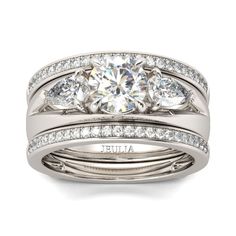 three stone engagement ring set with round diamonds on each side and channeled band, in 18k white gold