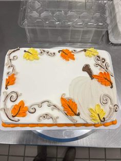 a cake with white frosting decorated with orange and yellow leaves