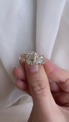 a woman's hand holding an old diamond ring