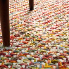 an area rug that has been made with yarn and wooden legs on the floor,