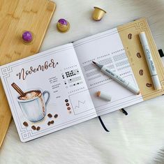 an open planner with coffee and spices on it next to a cup of hot chocolate