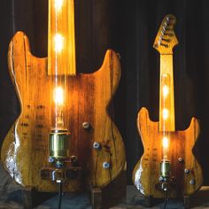 two wooden guitars with lights on them sitting next to each other