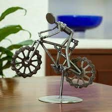 a metal bicycle on a wooden table next to a potted plant