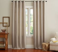 a living room with a white couch and two curtains hanging on the window sill