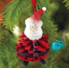 a pine cone ornament with a santa clause on it hanging from a christmas tree