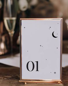 a table with a sign that says 10 on it and two glasses of wine in the background