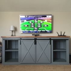 a flat screen tv mounted to the side of a gray entertainment center with sliding doors