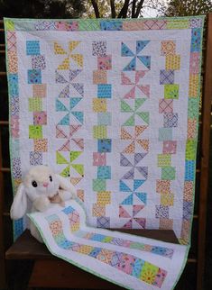 a stuffed animal sitting on top of a blanket next to a wooden bench and tree