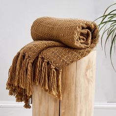 a brown blanket sitting on top of a wooden box next to a potted plant