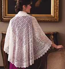 a woman standing in front of a painting wearing a white crocheted shawl