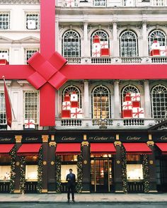 a man standing in front of a red building with christmas decorations on it's windows