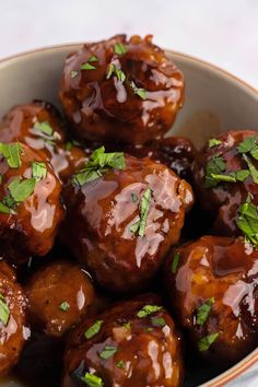 a bowl filled with meatballs covered in sauce and garnished with parsley