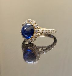 "DeKara Designs Collection Art Deco Inspired Extremely Elegant Halo Opal Diamond Engagement Ring. Metal- 90% Platinum, 10% Iridium. Stones- 1 Natural Oval Cabochon Ceylon Blue Sapphire 2.85 Carats, 26 Round Diamonds F-G Color VS1 Clarity 0.65 Carats. Size- 4-12 An Amazing Art Deco Inspired Ceylon Blue Sapphire Halo Diamond Engagement Ring Made in 18K Yellow Gold. The ring features a beautiful a beautiful Ceylon Blue Sapphire that is Oval in shape and cabochon cut. The sapphire is gracefully set Wedding Sapphire Ring In White Gold With Polished Finish, Luxury Sapphire Jewelry For Wedding, Classic Wedding Jewelry With Cabochon, Wedding Fine Jewelry With Cabochon, Cabochon Fine Jewelry For Weddings, Timeless Yellow Gold Sapphire Wedding Jewelry, Luxury Sapphire Halo Ring For Formal Occasions, Luxury Oval Cabochon Jewelry For Anniversary, Blue Cabochon Wedding Ring