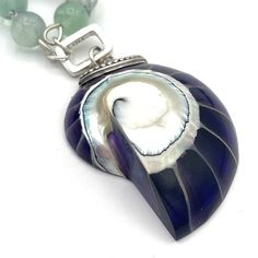 "Rainbows and mermaids are proof that imagination and beauty go hand in hand." Embrace your inner mermaid when wearing this gorgeous one of a kind gemstone pendant necklace. Hand-knotted Rainbow Fluorite gemstones in various shades of green, purple and blue reminds one of a mermaid's iridescent scales. Hanging from these genuine gem beads, is a vintage sterling silver and real nautilus shell pendant. The natural seashell is incased in purple resin to create a unique statement piece. A true treasure to add to your boho jewelry box. Real gemstone necklace composed of 8mm multicolor or rainbow Fluorite beads with a vintage sterling silver, real nautilus shell, and purple resin pendant. Approximately 28 inches in length including antique sterling silver and nautilus or ammonite shell pendant, Unique Shell Pendant Necklace As Gift, Unique Shell Necklace For Gift, Unique Pendant Shell Necklace As Gift, Unique Shell Pendant Necklace For Gift, Gemstone Beaded Shell Jewelry For Gifts, Unique Gemstone Necklace With Mother Of Pearl, Unique Mother Of Pearl Pendant Necklaces, Gift Necklace With Natural Stones And Abalone Shell, Abalone Shell Necklaces With Natural Stones For Gifts