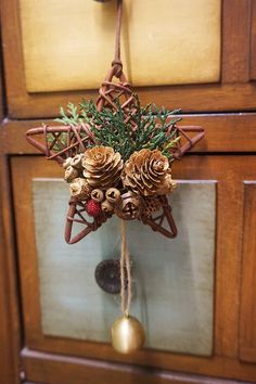 pine cones and berries are hanging from a door handle on a wooden cabinet with a gold ornament