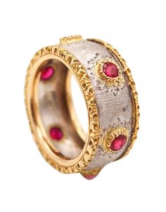 a gold and silver ring with red stones on it's sides, set against a white background