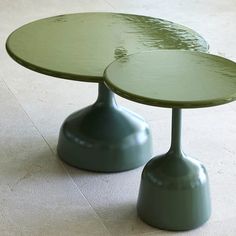 two green tables sitting on top of a white tile floor