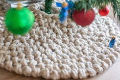 a crocheted christmas tree skirt with ornaments hanging from it