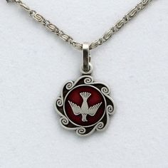 Red enameled Holy Spirit pendant with
18in. silver plated scroll chain. Red Symbolic Engraved Jewelry, Symbolic Red Pendant Jewelry, Red Metal Jewelry With Silver Chain, Silver Enamel Jewelry With Adjustable Chain, Red Enamel Round Pendant Necklace, Red Symbolic Sterling Silver Necklace, Silver Enamel Pendant Charm Necklaces, Silver Enamel Charm Necklace With Round Pendant, Silver Enamel Round Pendant Charm Necklace