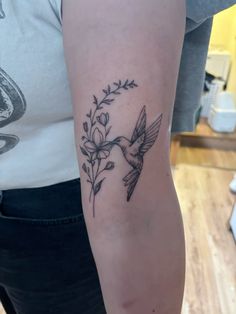 a woman's arm with a bird and flowers tattoo on the back of her left arm