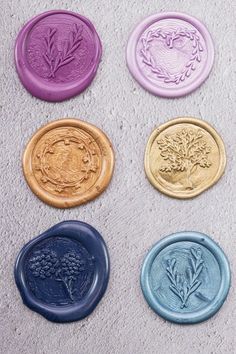 four different colored wax seals sitting on top of a cement floor next to each other