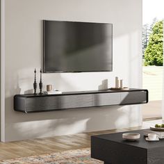 a flat screen tv mounted to the side of a wall above a coffee table in a living room