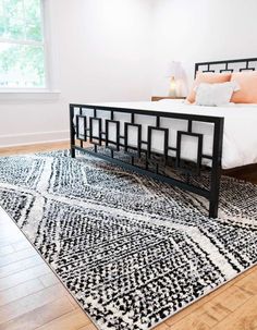 a bed sitting on top of a wooden floor next to a white and black rug