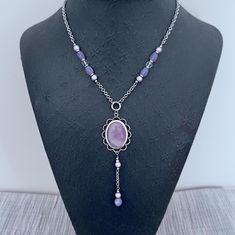 Amethyst oval stone pendant necklace with long drop and matching earrings. The necklace and earrings are sold as a set. The oval Amethyst cabochon is set into a silver filagree setting. The chain drop on the pendant measures 2 inches making the total drop of the pendant part 4 inches/10 cm in total. The silver stainless chain is inserted with a mix of clear and purple beads. The chain is finished at the length of 43cm/17 inches, with a 2 inch extension chain, also in stainless steel. The earring Purple Jewelry With Natural Stones, Purple Metal Jewelry With Natural Stones, Elegant Purple Long Drop Jewelry, Elegant Long Drop Purple Jewelry, Purple Jewelry With Natural Stones In Metal, Handmade Purple Costume Jewelry, Elegant Purple Wire Wrapped Jewelry, Purple Teardrop Necklace For Jewelry Making, Purple Wire Wrapped Long Drop Jewelry