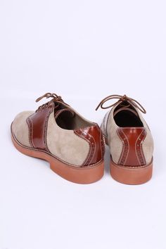 Casual two-tone 1950s-style oxford/saddle shoes with brogue pattern. These two-tone, 1950s-inspired, casual everyday oxfords feature an almond-shaped toe cap. The shoe is made of suede and features cognac brown full-grain leather with a brogue pattern on the backstay and around the vamp. The outsole is crafted from lightweight rubber with white stitching on the welt. These shoes were initially men's shoes. But here, it is also made for women. The shoes have a casual, sporty, and authentic 50s lo Retro Brown Leather Lace-up Shoes, Brown Oxford Leather Shoes With Rubber Heel Cap, Brown Leather Oxford Shoes With Rubber Heel Cap, Vintage Brown Lace-up Shoes With Rubber Sole, Brown Lace-up Shoes With Contrast Sole For Derby, Brown Oxfords With Brogue Detailing For Derby, Brown Dress Shoes With Rubber Heel Cap For Derby, Brown Cap Toe Oxfords With Brogue Detailing, Brown Brogue Oxfords For Derby