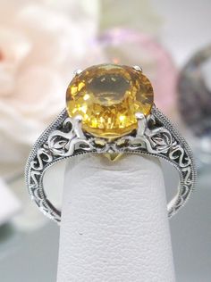 Natural Yellow Citrine Sterling Silver Ring Swan Design #D190 Introducing our Natural Yellow Citrine Swan Ring, D190, an exquisite piece that effortlessly blends elegance with vintage charm. Crafted with meticulous attention to detail, this Art Deco-inspired ring features a stunning natural yellow citrine gemstone nestled within a sterling silver filigree setting. At the heart of this ring is a full cut oval citrine, measuring 12mm in length and 10mm in width, radiating warmth and vibrancy. The Elegant Yellow Sapphire Gemstone Jewelry, Elegant Yellow Sapphire Jewelry Gift, Amber Yellow Sapphire Elegant Jewelry, Elegant Amber Jewelry With Yellow Sapphire, Amber Colored Yellow Sapphire Jewelry, Elegant Yellow Sapphire Round Jewelry, Elegant Amber Topaz Ring, Elegant Yellow Sapphire Jewelry, Classic White Gold Citrine Jewelry