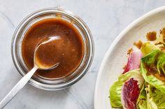 a white plate topped with lettuce next to a bowl of sauce