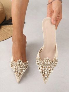 a woman's feet wearing white shoes with pearls on them